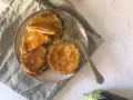 Cordon bleu di melanzane impanati e fritti, ripieni di prosciutto e formaggio filante, serviti su un piatto con una forchetta.