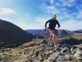Atleta corre su sentiero roccioso in montagna. Il fast hiking significato è correre in montagna con attrezzatura leggera.