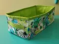Panier rectangulaire en tissu, doublé de pois verts. Son extérieur est orné d'un motif floral coloré, parfait pour ranger vos affaires avec style.