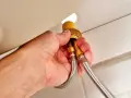 Hands disconnect braided water supply lines from a faucet base, a key step in how to remove kitchen faucet.
