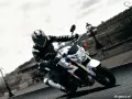 Motocyklista na białym Suzuki GSR 750 pokonuje zakręt. Nawet z potencjalnymi wadami, jazda nim to czysta przyjemność.