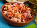 Oreja a la gallega, trozos de oreja de cerdo con pimentón en una cazuela de barro, listos para disfrutar.