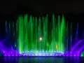 Spektakularna fontanna multimedialna we Wrocławiu nocą, tańczące strumienie wody w zielonych i fioletowych barwach tworzą magiczny pokaz.
