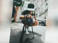 Młody fotograf w czapce z daszkiem trzyma aparat, zastanawiając się, ile zarabia fotograf w dzisiejszych czasach.