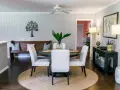 Elegante decoracion comedor pequeño con mesa redonda, sillas blancas, banco de madera y arte de árbol en la pared.