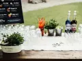 Stół z kieliszkami, butelkami syropów i miętą, gotowy na przygotowanie drinków na wesele. Przepisy na drinki są widoczne na tablicy w tle.