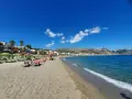 Spiaggia affollata a Giardini di Naxos, con lettini, ombrelloni e persone che si rilassano sotto il sole siciliano.