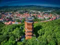 Nowoczesna wieża widokowa w otoczeniu zieleni, z panoramą miasta Wałbrzych i Sudetów Wałbrzyskich w tle.
