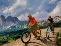 Due ciclisti si godono uno sport di montagna su sentieri sterrati con maestose vette sullo sfondo.