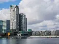 Nowoczesne budynki w Gdyni, w tym wysoki Sea Tower, nad wodą przy pochmurnym niebie.