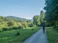 Osoba na rowerze przemierza malowniczą trasę rowerową Skoczów Wisła, otoczoną zielenią i wzgórzami.