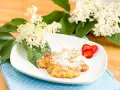 Fiori di sambuco fritti, spolverati di zucchero a velo, serviti su un piatto bianco con fragole fresche e decorati con fiori di sambuco.