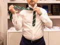 Uomo in camicia bianca che impara come fare il nodo alla cravatta verde a righe.