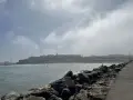Spokojna plaża z surferami i miastem w tle. Czy Maroko jest bezpiecznym krajem? Widok sugeruje, że tak, ludzie cieszą się słońcem i morzem.