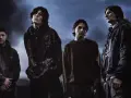 Członkowie Bring Me The Horizon stoją w mrocznej scenerii, z ognistymi płomieniami w tle.