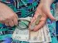Dłonie trzymające okulary, monety i polskie banknoty.