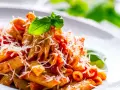 Penne al pomodoro con basilico fresco e parmigiano grattugiato, un classico tra i sughi per pasta.