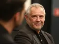 Uśmiechnięty Mikołaj Kondrat w szarym garniturze, rozmawiający z kimś niewidocznym na pierwszym planie.