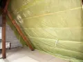 Na poddaszu rozłożona folia paroizolacyjna na drewnianych belkach, chroniąca przed wilgocią.