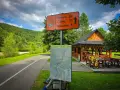 Znak szlaku rowerowego 611 Velo Soła wskazuje kierunki. Obok mapa i wiata z rowerzystą.