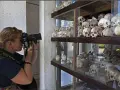 Kobieta fotografuje ludzkie czaszki na wystawie upamiętniającej pola śmierci w Kambodży.