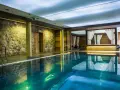 Basen w spa na Kaszubach. Kamienne ściany, turkusowa woda i zaciszne altany z białymi zasłonami tworzą atmosferę relaksu.