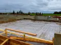 Fundament budowlany z zbrojeniem, przygotowany pod wylanie betonu. Widać betonowe ściany fundamentowe i siatkę stalową na podłożu.
