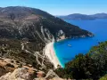 Widok na plażę Myrtos, jedno z najpiękniejszych miejsc na Kefalonii. Kręta droga prowadzi do białego piasku i turkusowej wody.