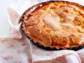 Une délicieuse tarte au sucre dorée, saupoudrée de cristaux de sucre, repose sur une serviette à motifs floraux roses.