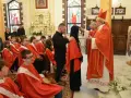 Biskup udziela sakramentu bierzmowania. Ceremonia, choć uroczysta, nie trwa długo. Młodzi ludzie w czerwonych szatach czekają na swoją kolej.