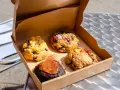 Vier köstliche, hausgemachte Cookies in einer Pappschachtel – die besten Cookies Berlins, bereit zum Genießen.
