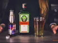 Butelka Jägermeister, puszka Red Bull i szklanka z drinkiem. Jägermeister to niemiecki likier ziołowy, często mieszany z napojami energetycznymi.