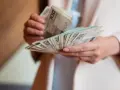 Dłonie liczą banknoty 100 zł. Zastanawiasz się, ile bierze komornik za alimenty?