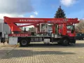 Czerwony podnośnik koszowy WUMAG WT 450 z koszem roboczym i wysięgnikiem. Na pojeździe widnieje napis WWW.PODNOSNIKI-TDS.PL.