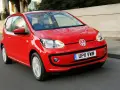Czerwony Volkswagen up! pędzi po miejskiej drodze, odbijając światła miasta w swojej lśniącej karoserii.
