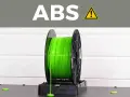A spool of bright green ABS plastic filament, commonly used for 3D printing durable parts.