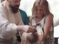 A priest performs a baptism, pouring water on a baby's head. The mother smiles, holding her child. This image captures the sacred moment of how to baptize someone.
