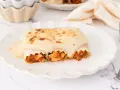 Canelones de atún gratinados con bechamel cremosa, listos para disfrutar en un plato blanco con borde ondulado.