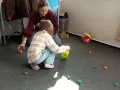 Dzieci bawią się na dywanie, zbierając małe, kolorowe figurki. Www.
