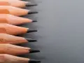 Filas de lápices de madera con puntas afiladas, listos para dibujar. La dureza de los lápices varía, ofreciendo distintas tonalidades.