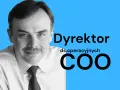 Mężczyzna w białej koszuli i krawacie, z wąsami, uśmiecha się. Obok jego twarzy widnieje napis "Dyrektor ds. operacyjnych COO", podkreślający jego stanowisko.