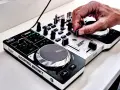 Dłoń DJ-a miksuje szybkie piosenki do tańca na kontrolerze Hercules DJControl Instinct.