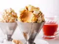 Cremiges Karamell-Popcorn-Eis in einem Metallbecher, garniert mit knusprigem Popcorn. Ein süßer Genuss!