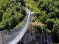 Un avventuroso percorso ponte tibetano si snoda tra rocce e fitta vegetazione, offrendo una vista mozzafiato sulla valle.