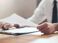 Dłoń trzyma dokumenty, przygotowując epuap zgłoszenie najmu okazjonalnego.