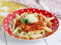 Macarrones con pollo en salsa roja, gratinados con queso y decorados con menta. Un plato delicioso y fácil de preparar.