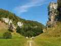 Słoneczna pogoda zachęca do wędrówki po szlakach Doliny Kobylańskiej. Widać rowerzystę i wspinaczy na skale.