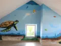 Fresque dessin d'un monde sous-marin avec une tortue, des poissons, une baleine et des coraux.