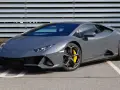 Szary Lamborghini Huracan z żółtymi zaciskami hamulcowymi na tle metalowej ściany.