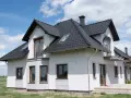 Nowoczesny dom z białymi boniami na elewacji, czarnym dachem i brązowymi oknami.